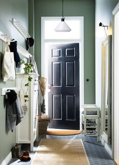 an entryway with a black door and white trim on the walls, carpeted flooring and potted plants