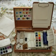 an artist's box with watercolors, paint and brushes