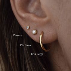 a woman's ear with two small white pearls on the inside of her ear