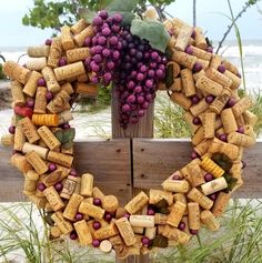 a wreath made out of wine corks on a wooden fence next to the beach