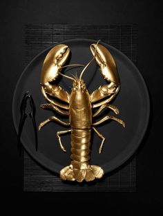 two golden lobsters on a black plate