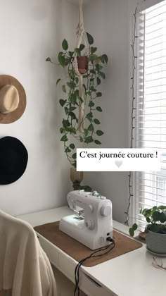 a sewing machine sitting on top of a table next to a potted green plant