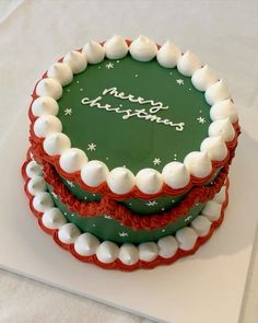 a green and red cake with white frosting on it's top sitting on a table