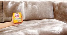 a person holding a packet of food sitting on a couch in front of a pillow