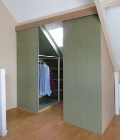 an open closet in the corner of a room with clothes hanging on hangers, and a wooden floor