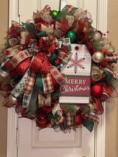 a christmas wreath on the front door with a tag hanging from it's side