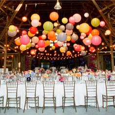 a large room with tables and chairs covered in paper lanterns hanging from the rafters