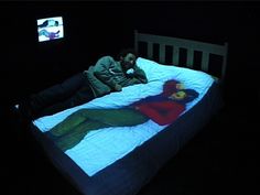 a person laying on a bed in the dark with a projected image of a woman