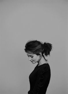 a black and white photo of a woman with her hair in a pony tail bun