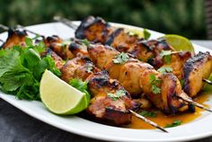 chicken skewers with cilantro and lime on a white plate