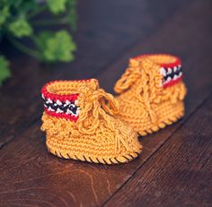 a pair of yellow crocheted baby booties sitting on top of a wooden floor