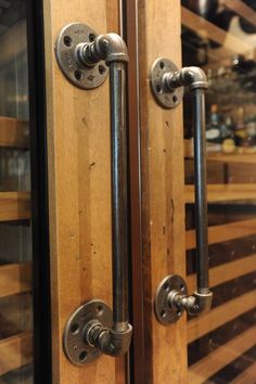 two wooden doors with metal handles and knobs in a room full of wine bottles