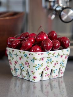 a bowl filled with cherries sitting on top of a counter