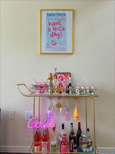 a bar cart filled with liquor bottles and glasses next to a framed poster on the wall