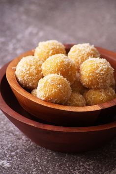 a wooden bowl filled with sugar covered donuts