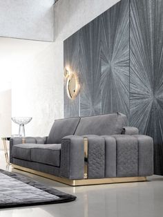 a modern living room with grey couches and gold accents on the wall, along with a rug