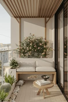 a white couch sitting on top of a wooden floor next to a table and potted plants