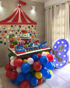 a circus themed birthday party with balloons, cake and number 3 on the table in front of it