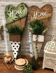 three wooden heart shaped signs sitting on top of a table next to potted plants