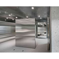 an empty room with mirrors and lights on the ceiling, in front of a concrete wall