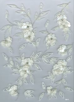 some white flowers and leaves on a gray background with silver foiled threadwork in the middle