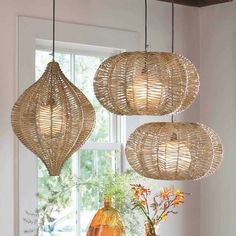 three hanging lights made out of wicker in front of a window with potted plants and vases