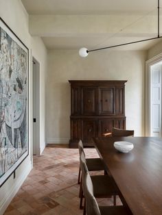 a dining room table with chairs and a large painting on the wall behind it in front of a doorway