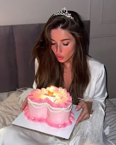 a woman is blowing out the candles on her birthday cake while wearing a tiara