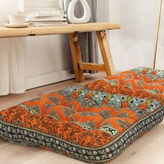 an orange and black cushion sitting on top of a wooden floor