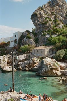 people are swimming in the water near some rocks