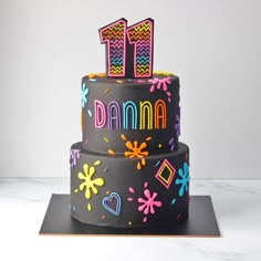 a decorated birthday cake with the number 11 on it's top tier and colorful decorations