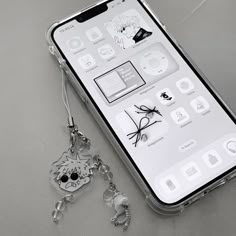 a cell phone with a keychain attached to it's back cover and an image of a cat on the screen