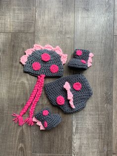 two crocheted hats, one with pink and black dots on it sitting on top of a wooden floor