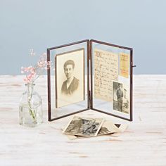 an open book sitting on top of a table next to a vase filled with flowers