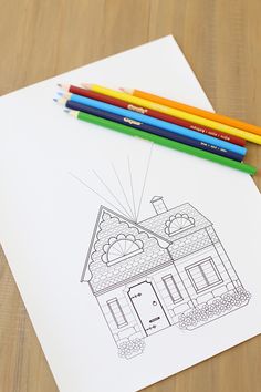 a drawing of a house with colored pencils next to it on top of a table