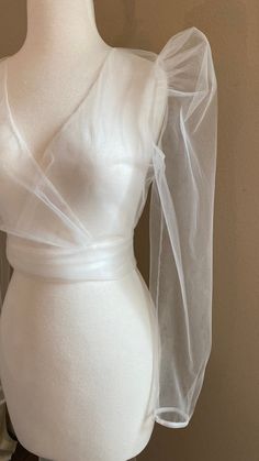 a mannequin wearing a white dress with sheer fabric on the shoulders and sleeves