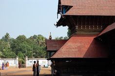 some people are standing in front of an old wooden building with red shingles on the roof