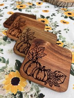 three wooden coasters sitting on top of a table covered in flowers and pumpkins