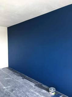 an empty room with a blue wall and some paint on the floor in front of it