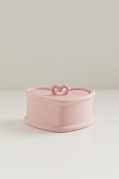 a pink heart shaped container sitting on top of a table