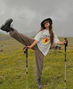 a woman standing on top of two ski poles in the middle of a grass covered field