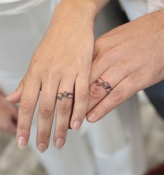 two people holding hands with tattoos on their fingers