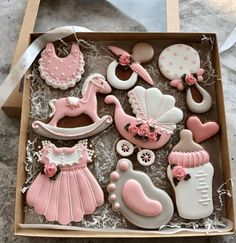 a box filled with lots of pink and white baby shower cookies on top of a table