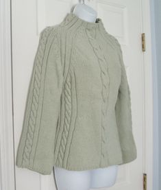 a white mannequin wearing a green sweater