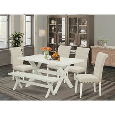 a white dining table with four chairs and a bench in front of it on a rug