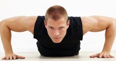 a man in black shirt doing push ups on white floor with his hands behind his head