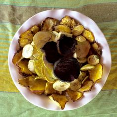 a white plate topped with sliced up fruit and nuts on top of a green table cloth