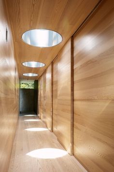 the hallway is lined with wooden walls and flooring, along with recessed lighting