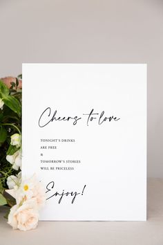 a white card with the words cheers of love written on it next to some flowers