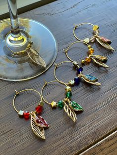 four wine glasses sitting next to each other on top of a wooden table with charms hanging from them